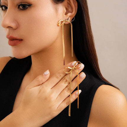 Woman wearing gold bow-shaped earrings with a neutral background