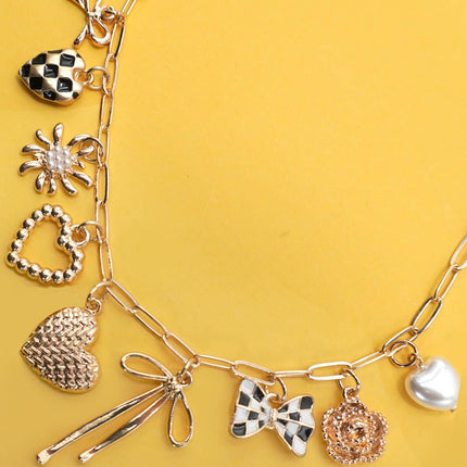 Gold necklace with various charms on a yellow background