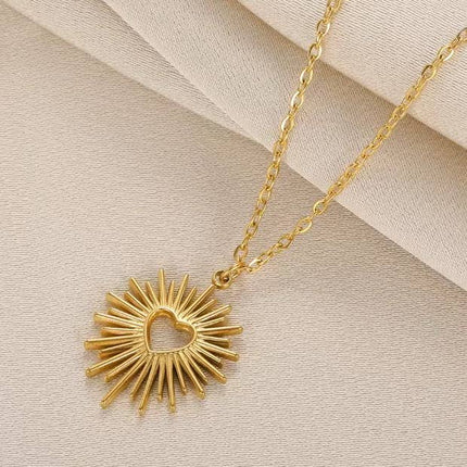 Gold necklace with a sunburst pendant on a beige background
