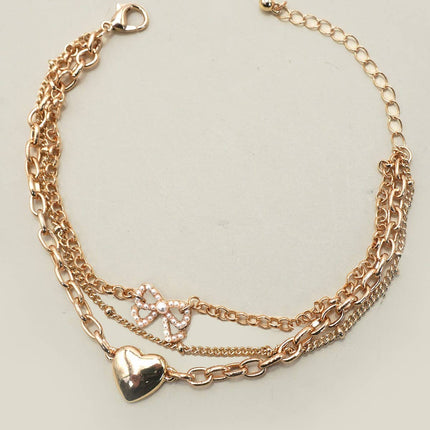 Multi-layer gold charm bracelet with heart charm and pearl bow on chain links, 7.5” with 2” extender