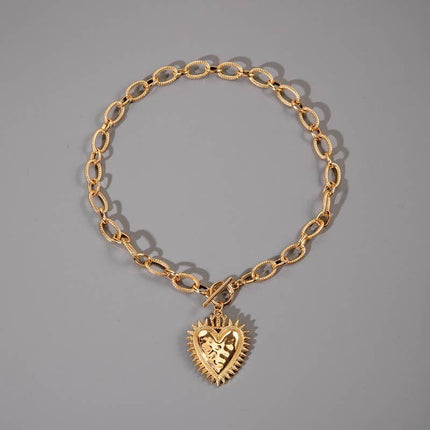 Gold chunky chain necklace with a front toggle clasp and oversized spiked heart pendant