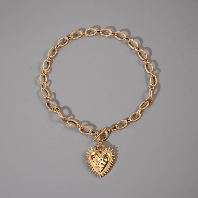 Gold chunky chain necklace with a front toggle clasp and oversized spiked heart pendant