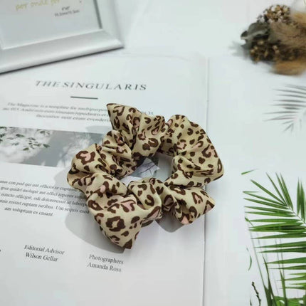 Leopard print scrunchie on a magazine with text and greenery
