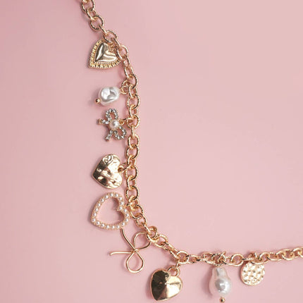 Gold-plated charm bracelet with bow, heart, pearl, and textured disc charms, 6.5” with 2” adjustable extender