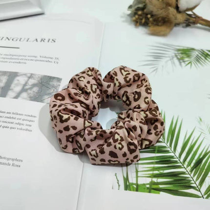 Leopard print scrunchie on a magazine with green leaves