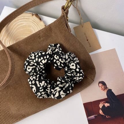 Leopard print scrunchie on a brown textured bag with a magazine in the background
