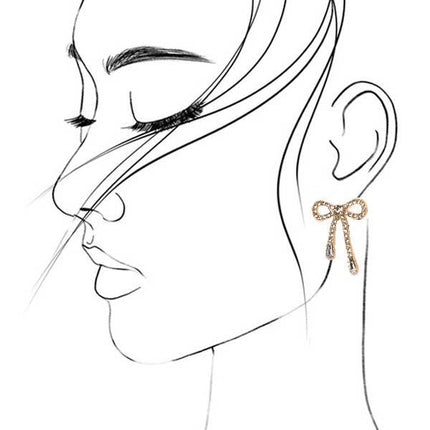 Gold rhinestone bow drop earrings with a delicate dangling design, shown worn on the ear and displayed against a bright pink background.