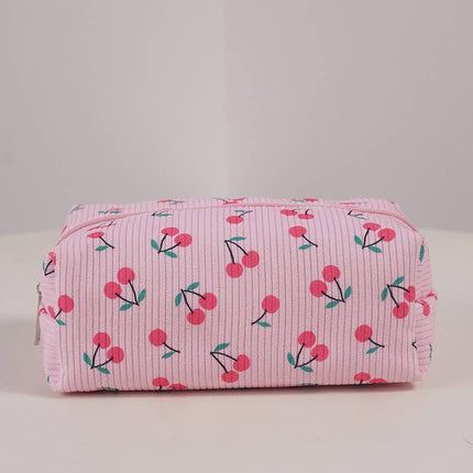 Pink toiletry bag with cherry pattern on a light gray background