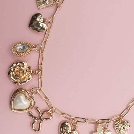 Gold charm bracelet with various charms on a pink background