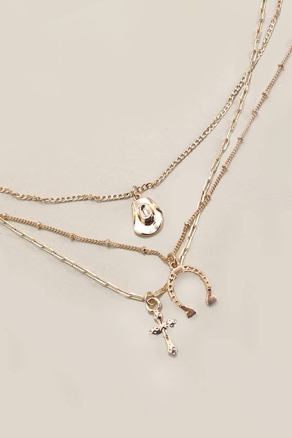 Gold plated multi-layer western inspired charm necklace with dangling horseshoe, porcelain hat and cross charms 
