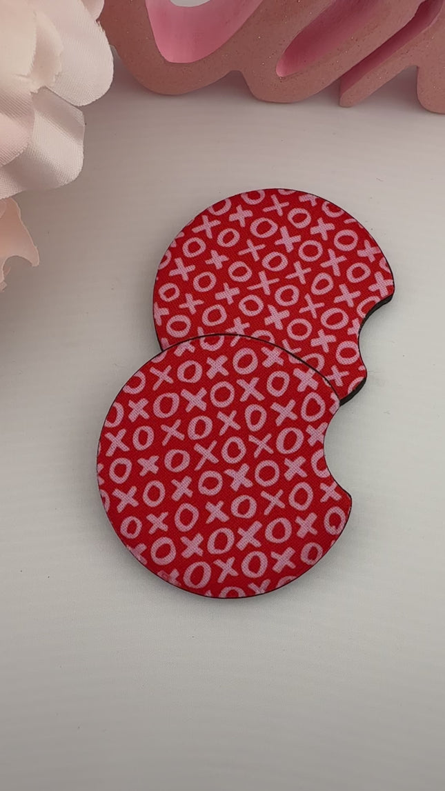 Two Valentine’s Day–themed neoprene car coasters with heart and love patterns, shown inside gift-ready packaging and styled on a neutral background.