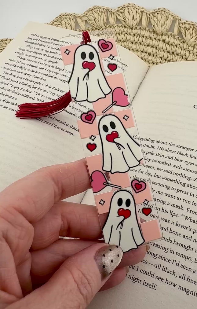 Handmade acrylic Valentine’s Day bookmarks featuring pink and red heart-themed designs with tassels, styled on open books for a cozy, festive reading aesthetic.